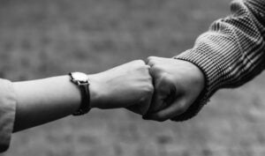 kahden ihmisen kädet antamassa toisilleen fistbumpin