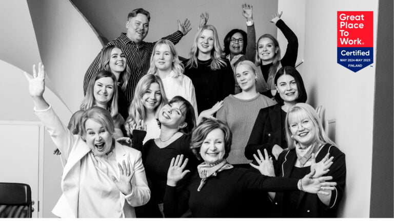 People of Ahjo smile at the camera and rejoice. In the upper-right corner, there is a 'Great Place to Work' certificate.